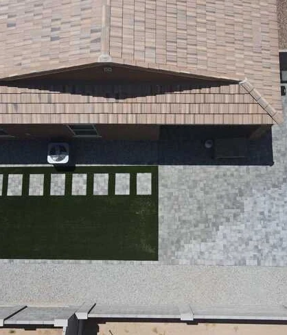 Overhead view of a gray paver patio, turf rectangle and aligned stepping stones.
