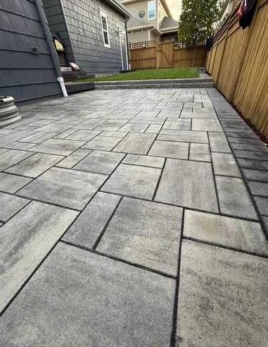Close view across a gray paver patio showing rectangular stone pattern and dark joints.