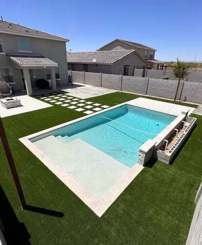 Rectangular swimming pool framed by artificial turf, pale pavers and a geometric stepping-stone path.