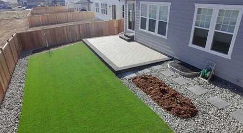 Green turf lawn and raised concrete patio with gravel edges and planting space.